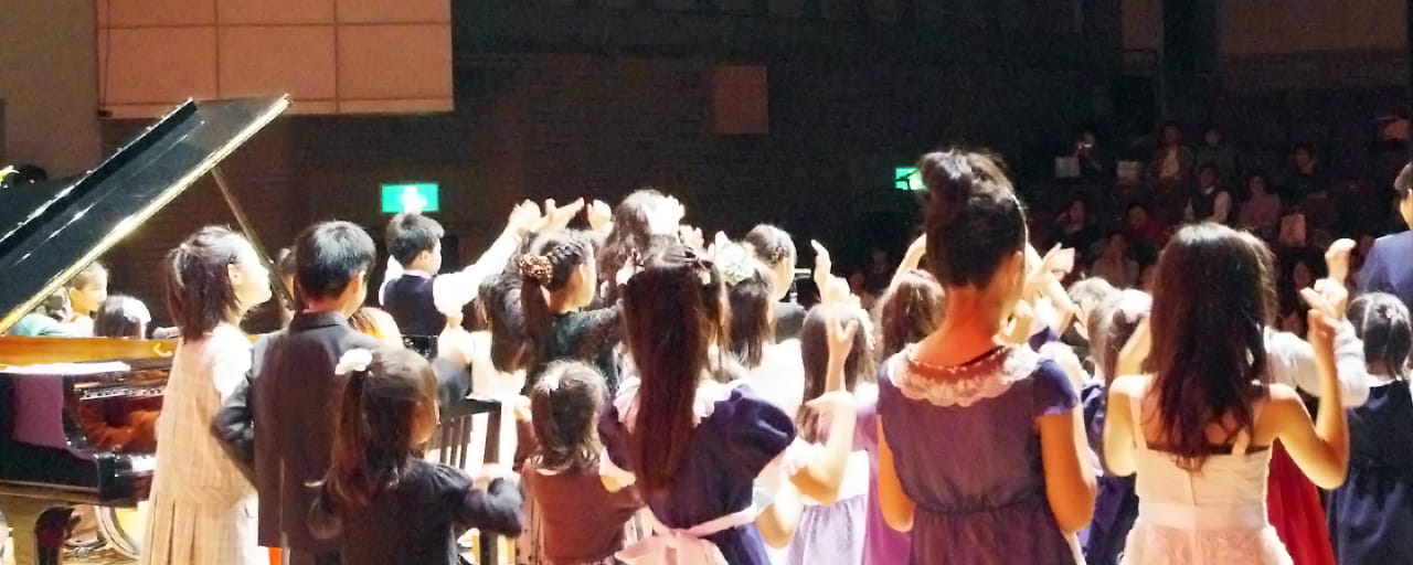 写真：客席に向かって子どもたちが大集合しているピアノ発表会のステージ