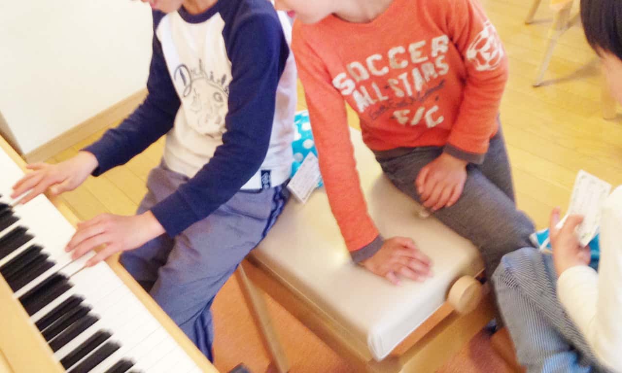 写真:お互いのピアノの腕前を見せ合う男の子三人