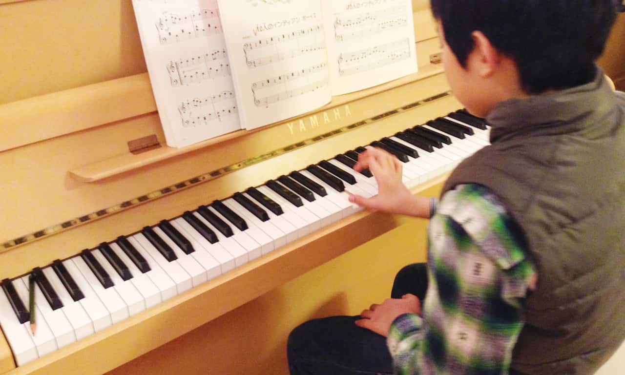 写真:ゆっくり丁寧に右手でピアノを弾く男の子