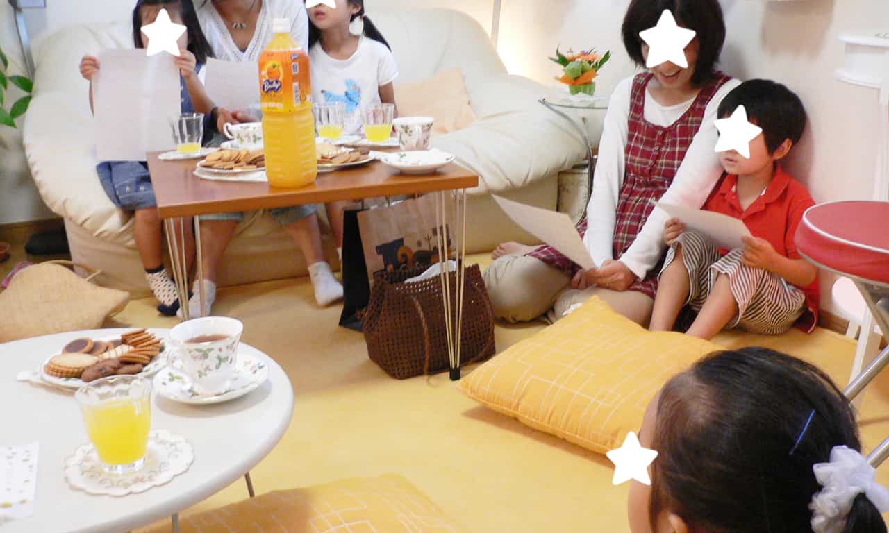 写真：クッションを敷いた黄色いカーペットの上や、白いソファーに思い思いに座って歌う子どもたちとお母さんたち