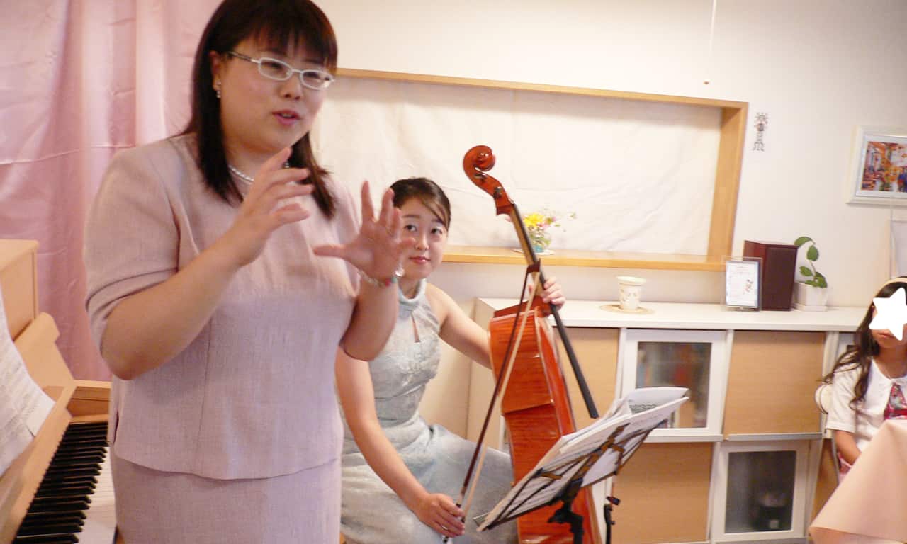 写真：身振り手振りを交えて話す当教室ピアノ講師の福田りえと、それを見ているチェリスト三澤亜美さんと生徒さんたち