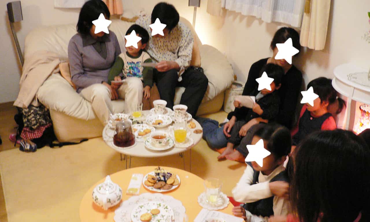 写真：ソファー席とカーペットを敷いた床に座って歌う子どもの生徒さんたちと親御さんたち