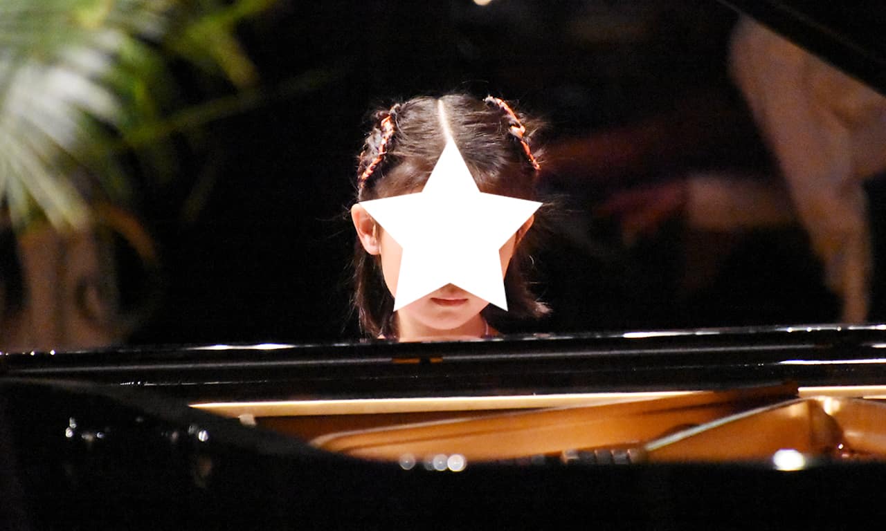 写真：ピアノ・ソロ演奏の女の子を正面から捉えた写真