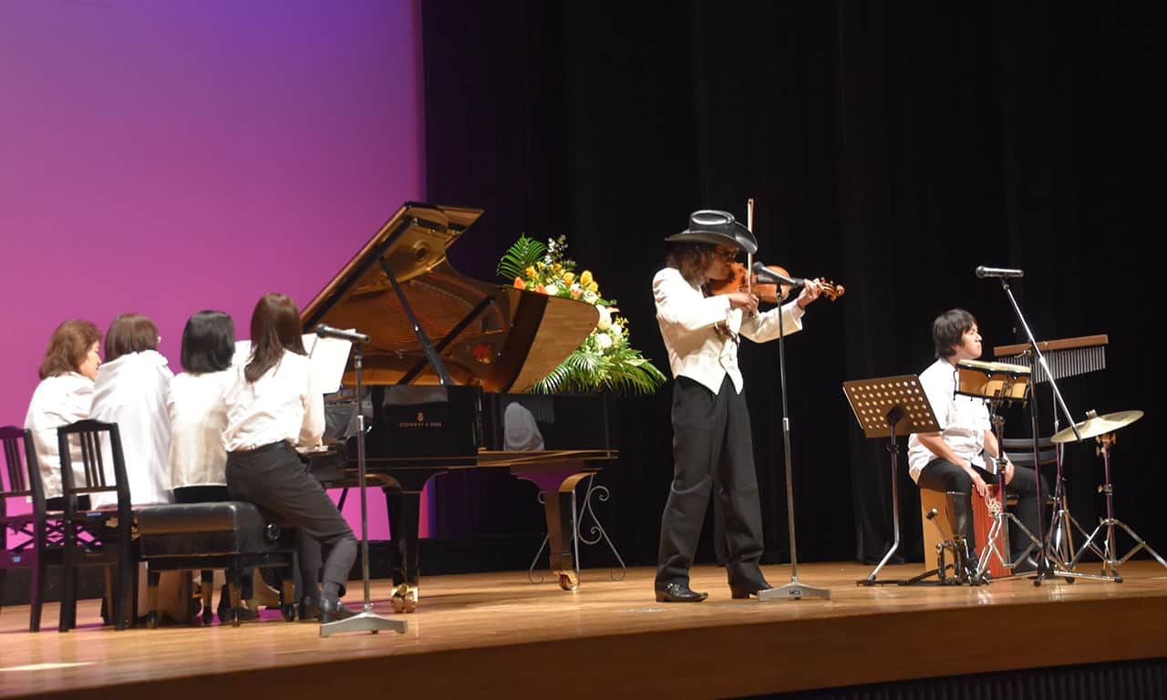 写真：ピアノの4人8手連弾とソロ・ヴァイオリン、パーカッションのアンサブルの様子