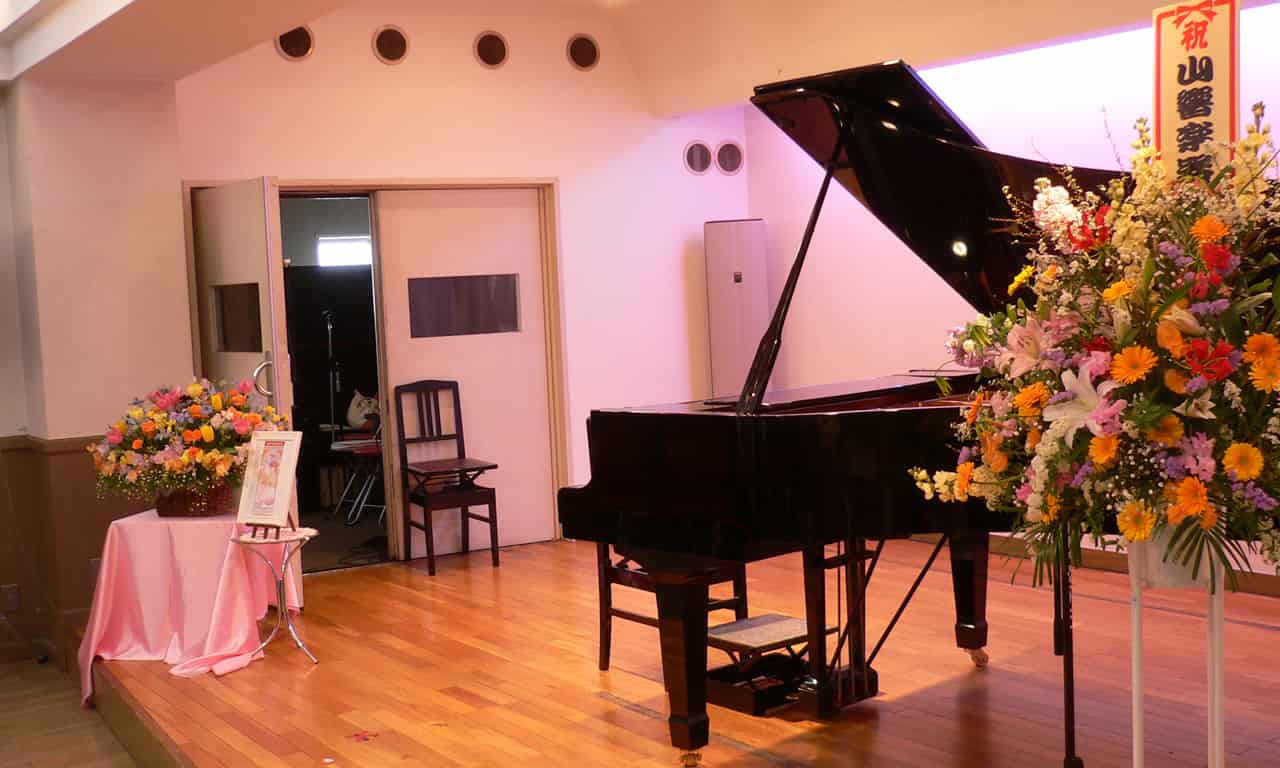 写真：ステージのグランドピアノの傍らに置いてある大きな花
