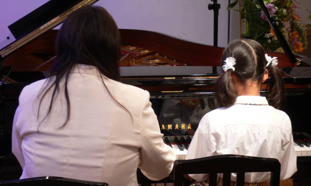 写真：講師と連弾している女の子の後ろ姿