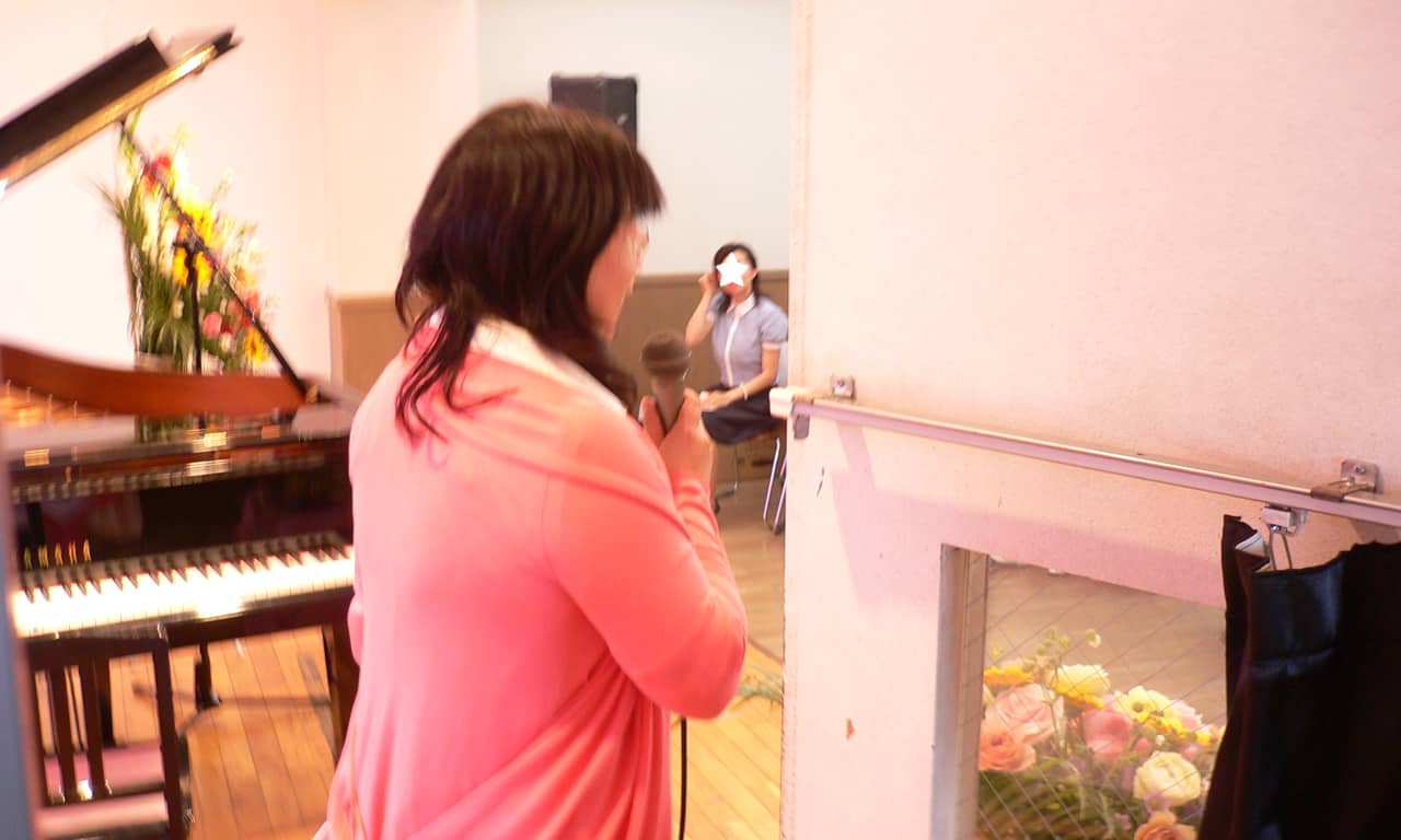 写真：ステージ上で客席に向かい、マイクを手に挨拶する講師