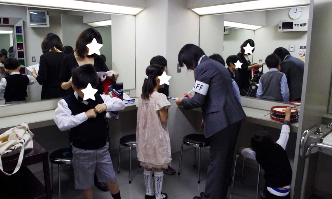 写真：演奏者用楽屋で出番前の子どもたちの確認を行っているスタッフの様子