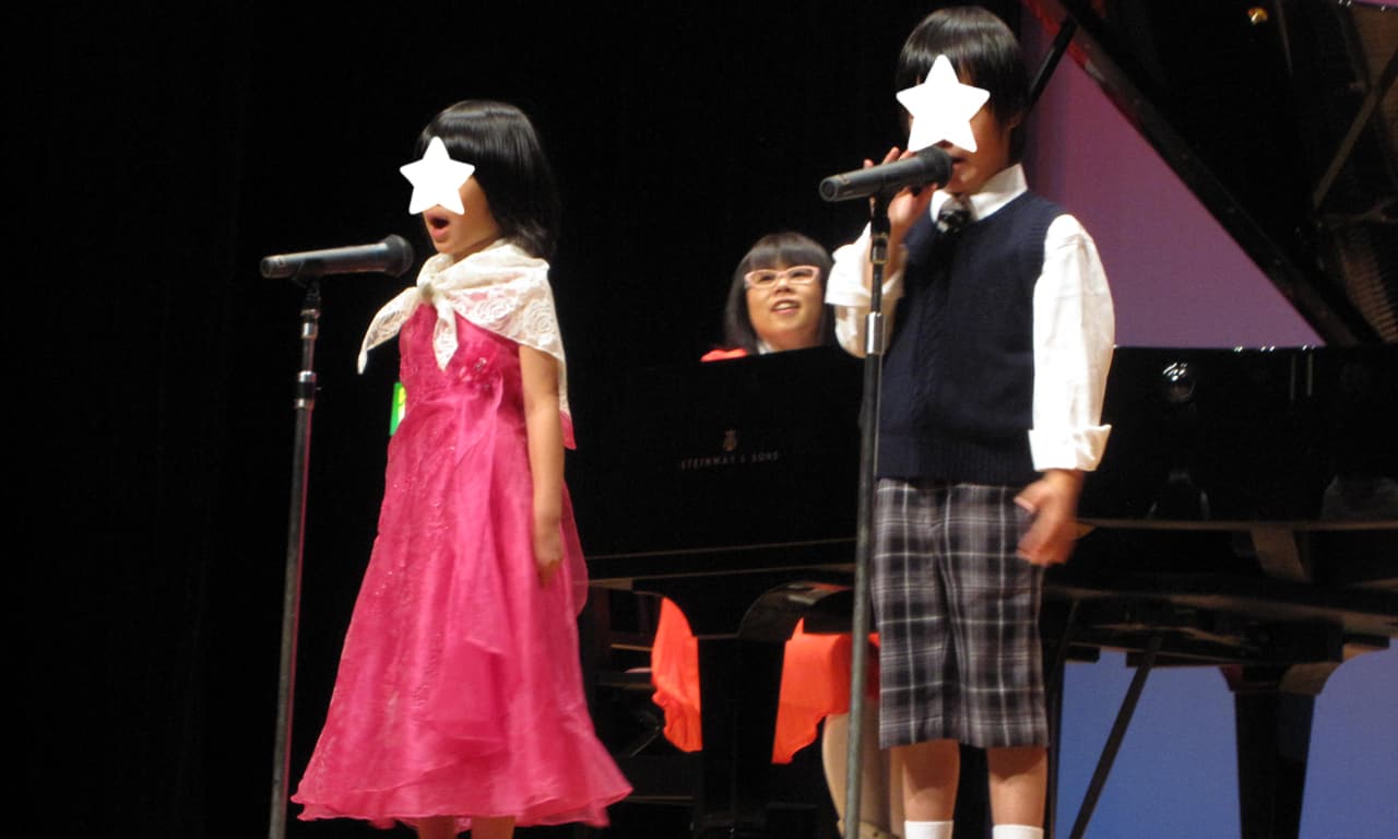 写真：講師のピアノ伴奏で歌っているお兄ちゃんと妹ちゃん