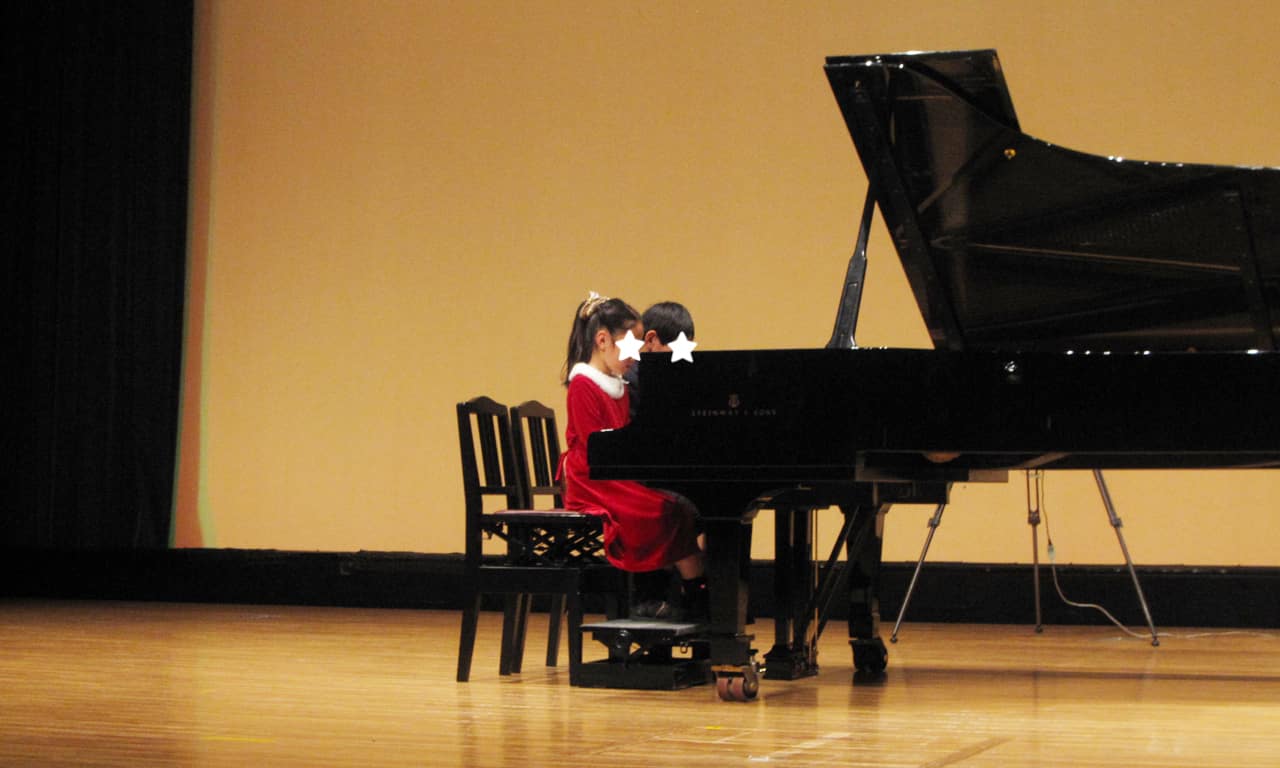 写真：大きなグランドピアノで連弾をするお兄ちゃんと妹ちゃん