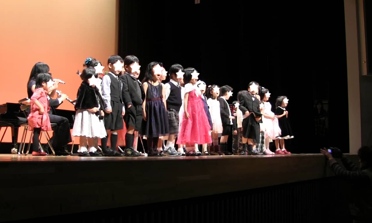 写真：並んで歌っているたくさんの小さな子どもたちを、ステージ下から見た様子