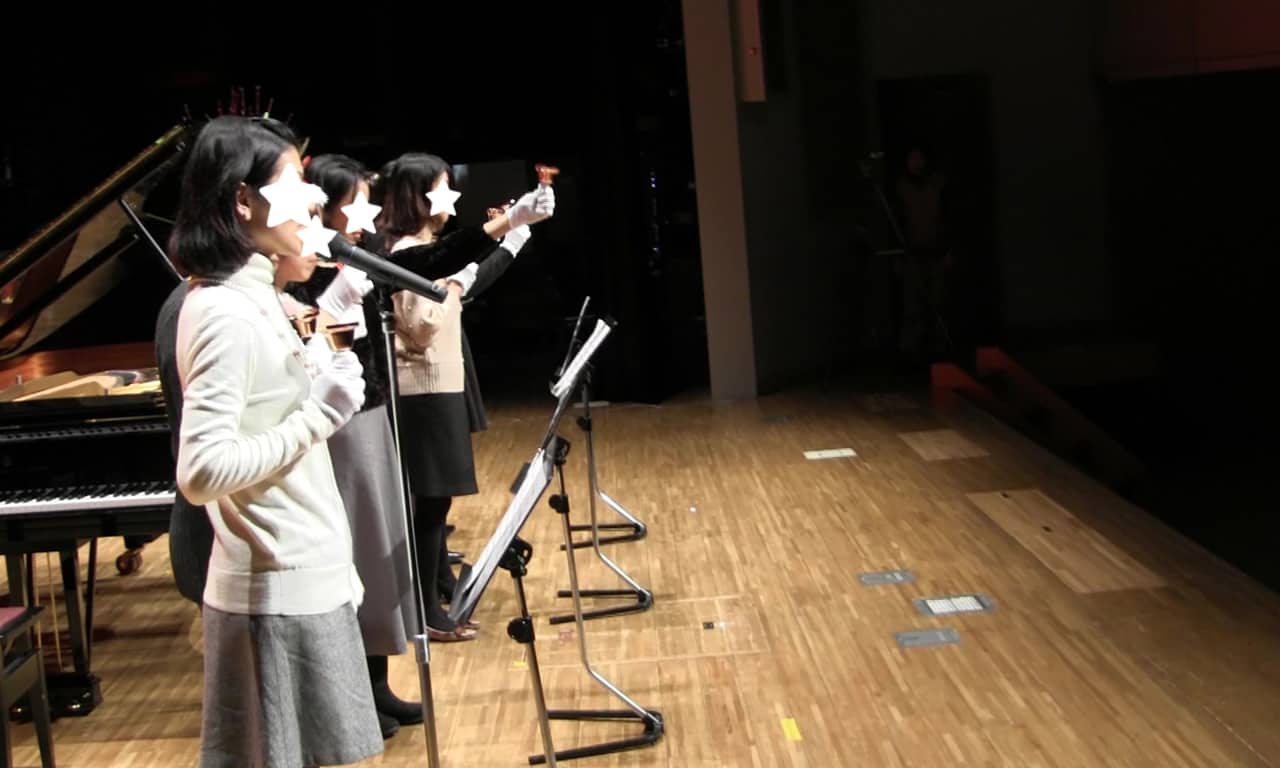 写真：ハンドベルを手にステージ上に並んで演奏するママたちの様子
