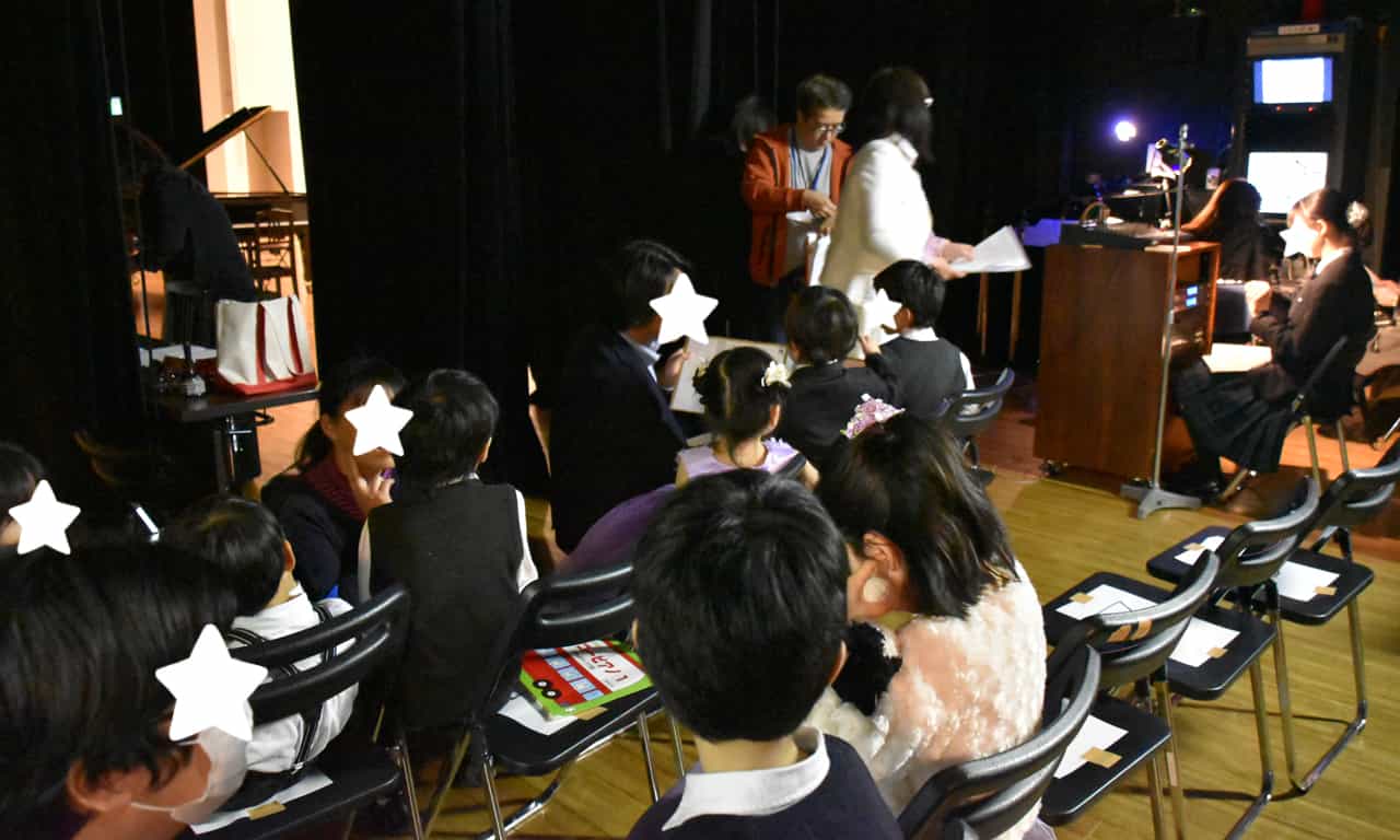 写真：舞台袖で椅子に座って演奏順を待っている子どもたちの様子