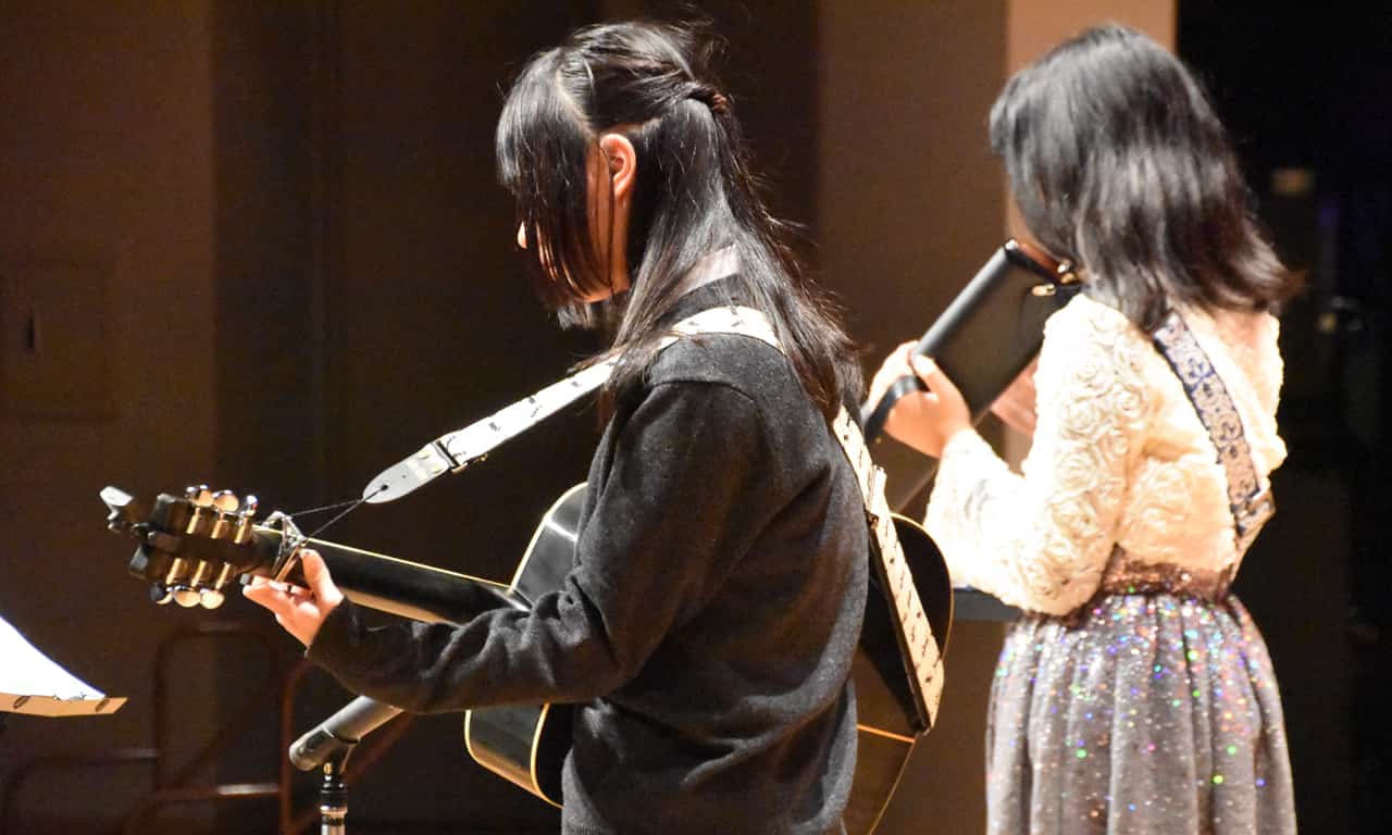 写真：ギターと鍵盤ハーモニカでアンサンブル演奏している二人の女子中学生