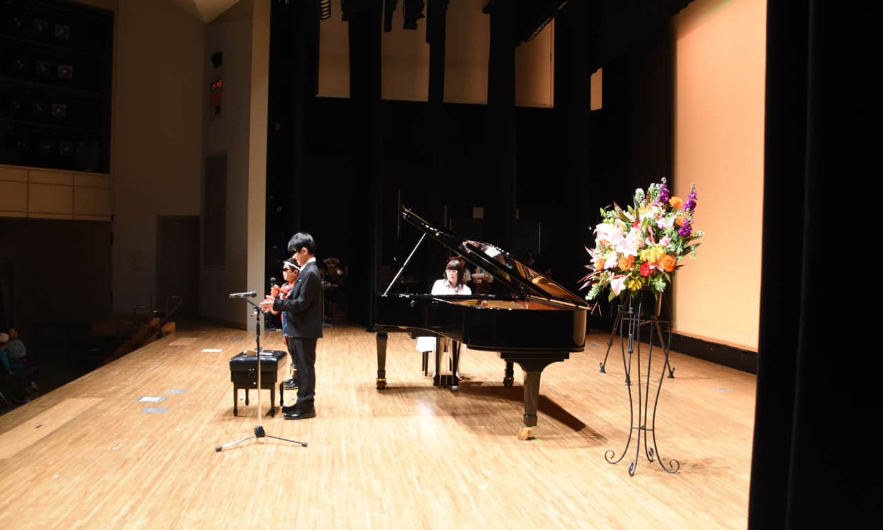 写真：舞台袖から見た歌とパーカッションでアンサンブルする男の子二人の様子