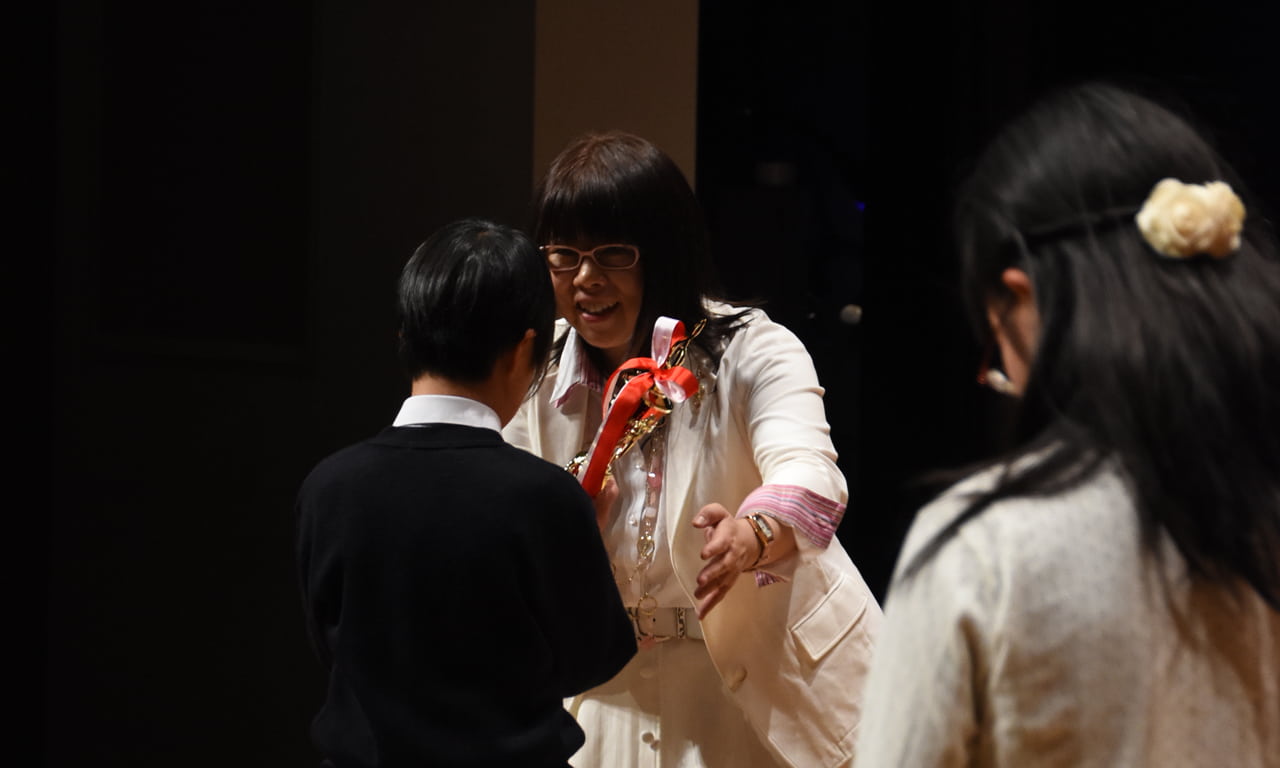 写真：発表会5回出演賞のトロフィーを受け取っている男の子