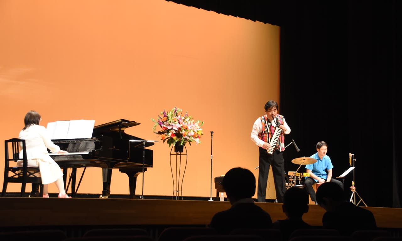写真：ピアノとパーカッションとでアンサンブルする松田昌先生の鍵盤ハーモニカによるゲスト演奏をステージ下から見た様子