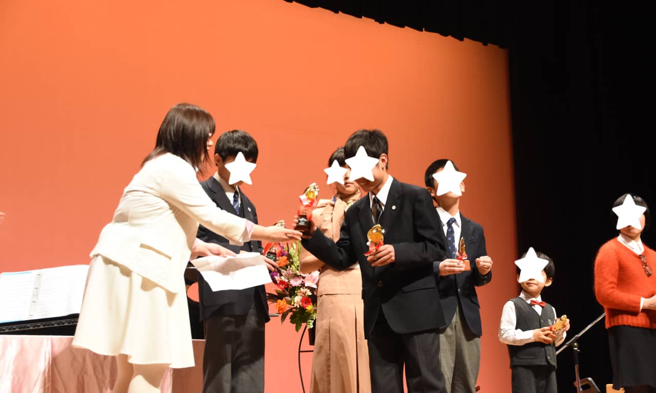 写真：ステージに並び講師からトロフィーを受け取っているオーディエンス賞受賞者の生徒さんたち